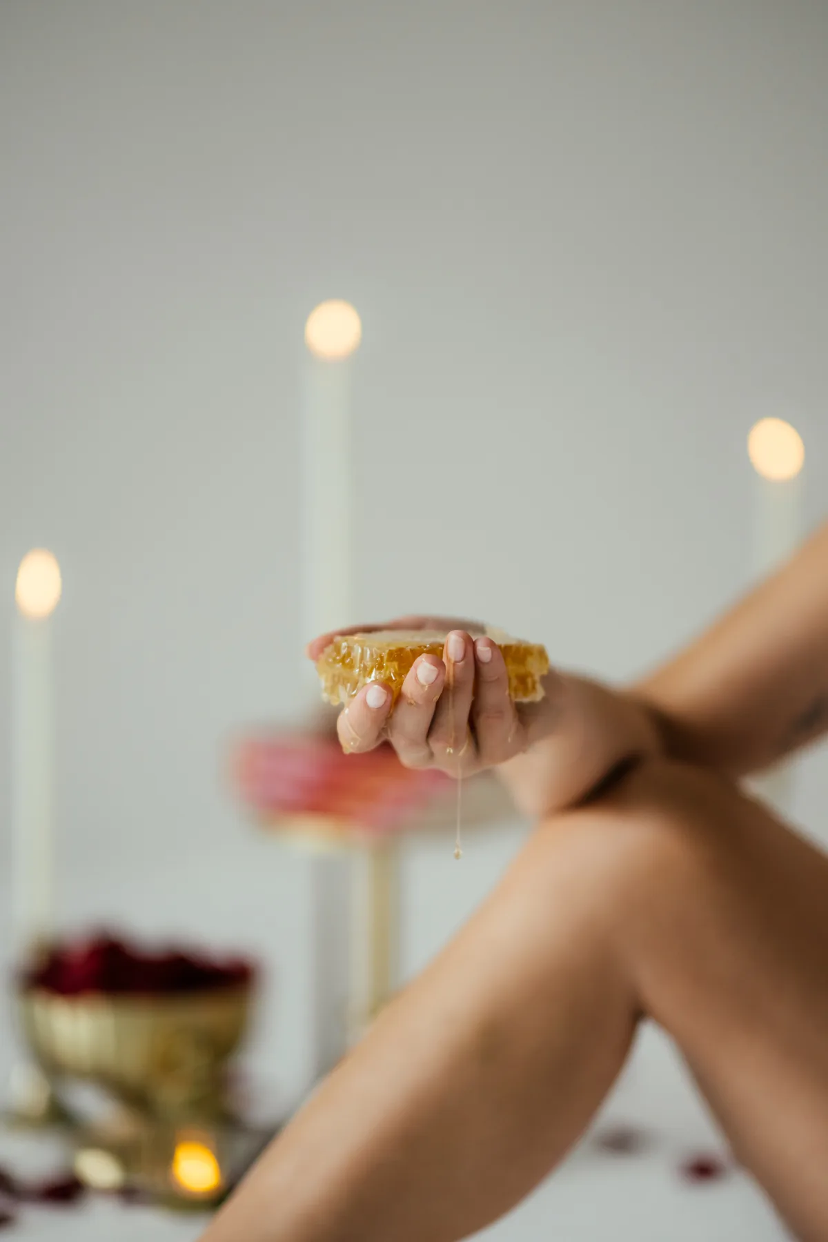 A hand holding fresh honeycomb dripping with honey
